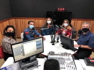 Imagem: Quatro pessoas ao redor de uma mesa de gravação na rádio universitária.